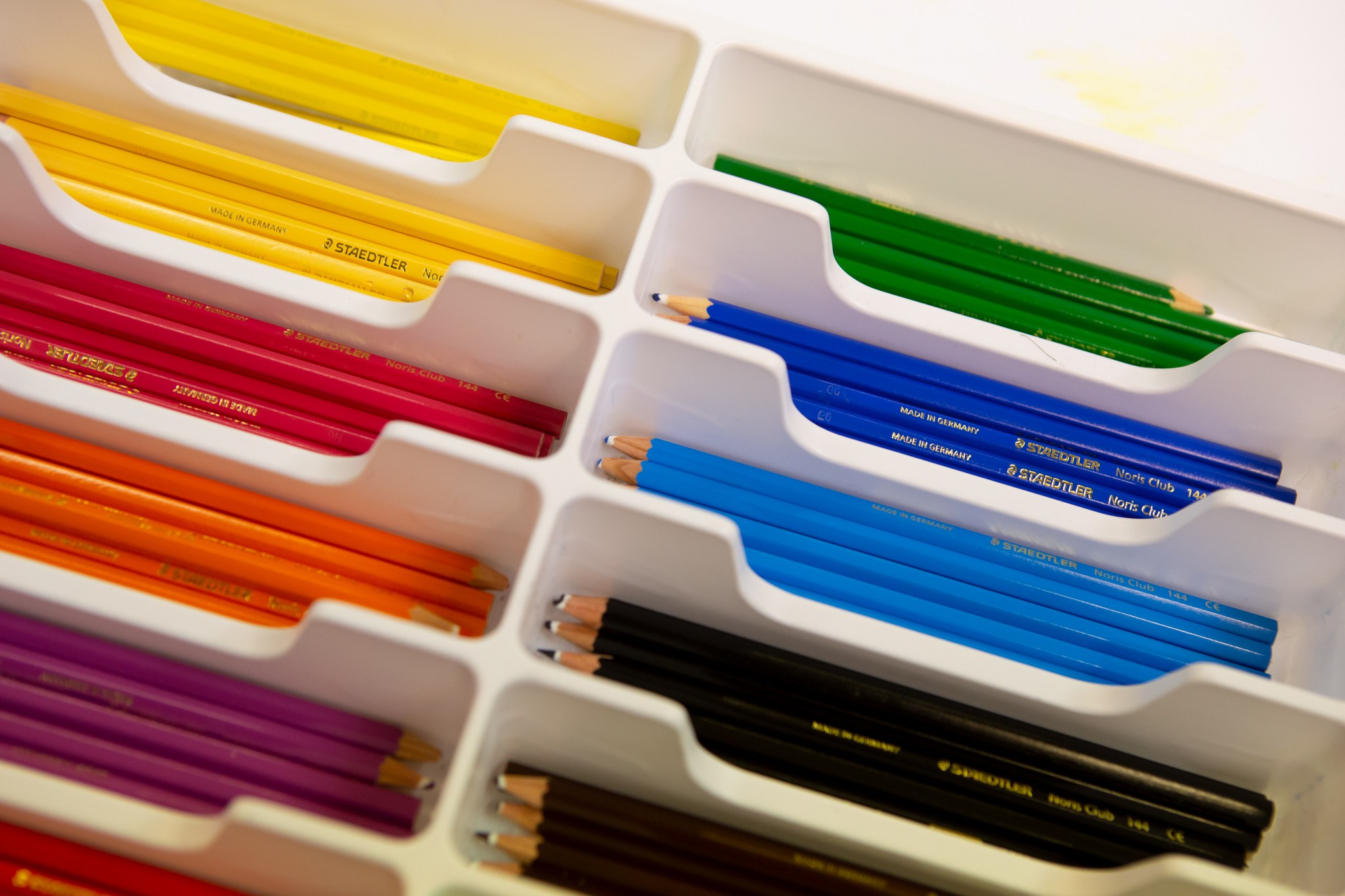 Eri värisiä kyniä lajiteltua kynälaatikkoon.