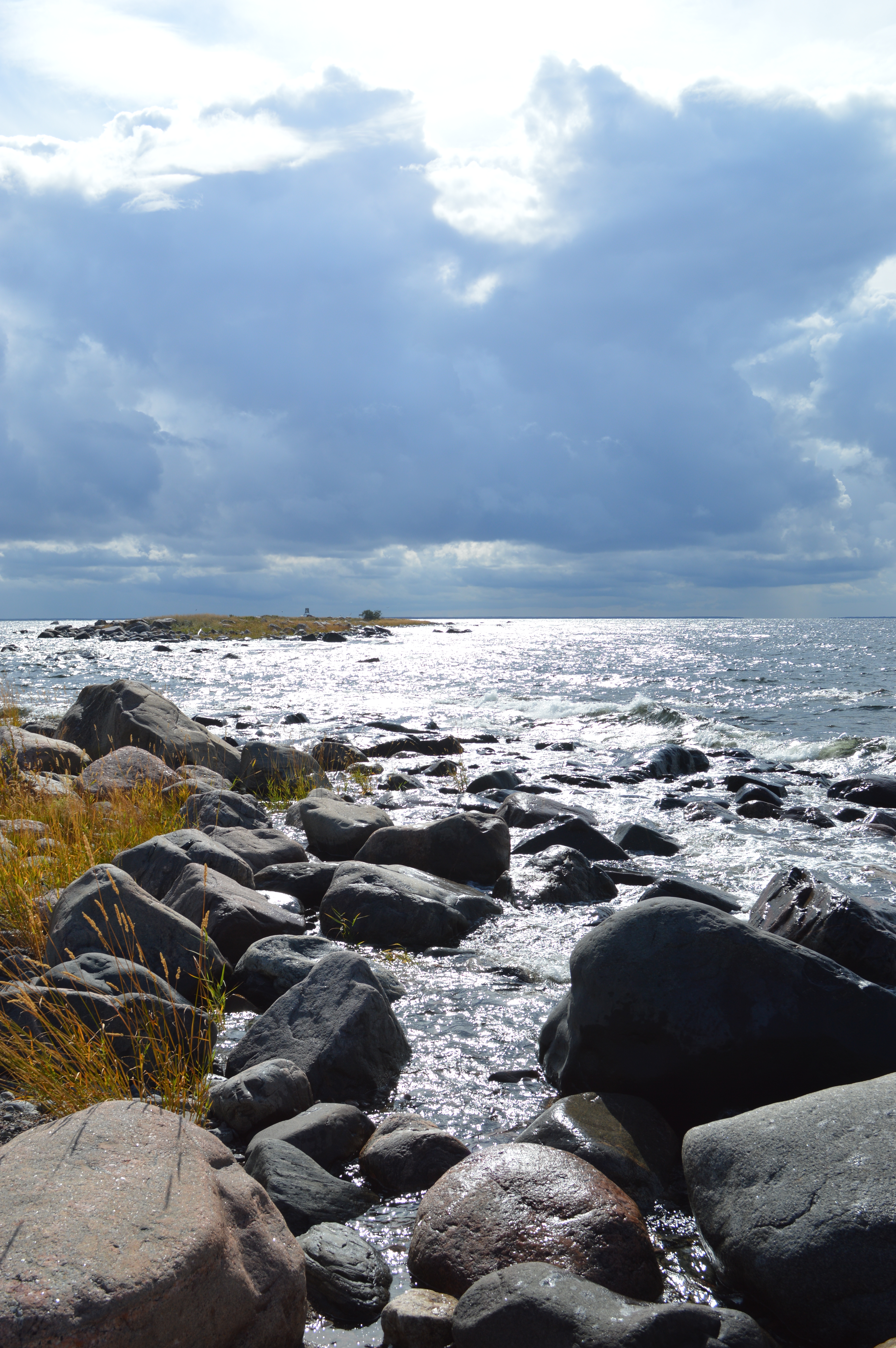 Kivikkoinen ranta-alue, tummat pilvet taustalla.