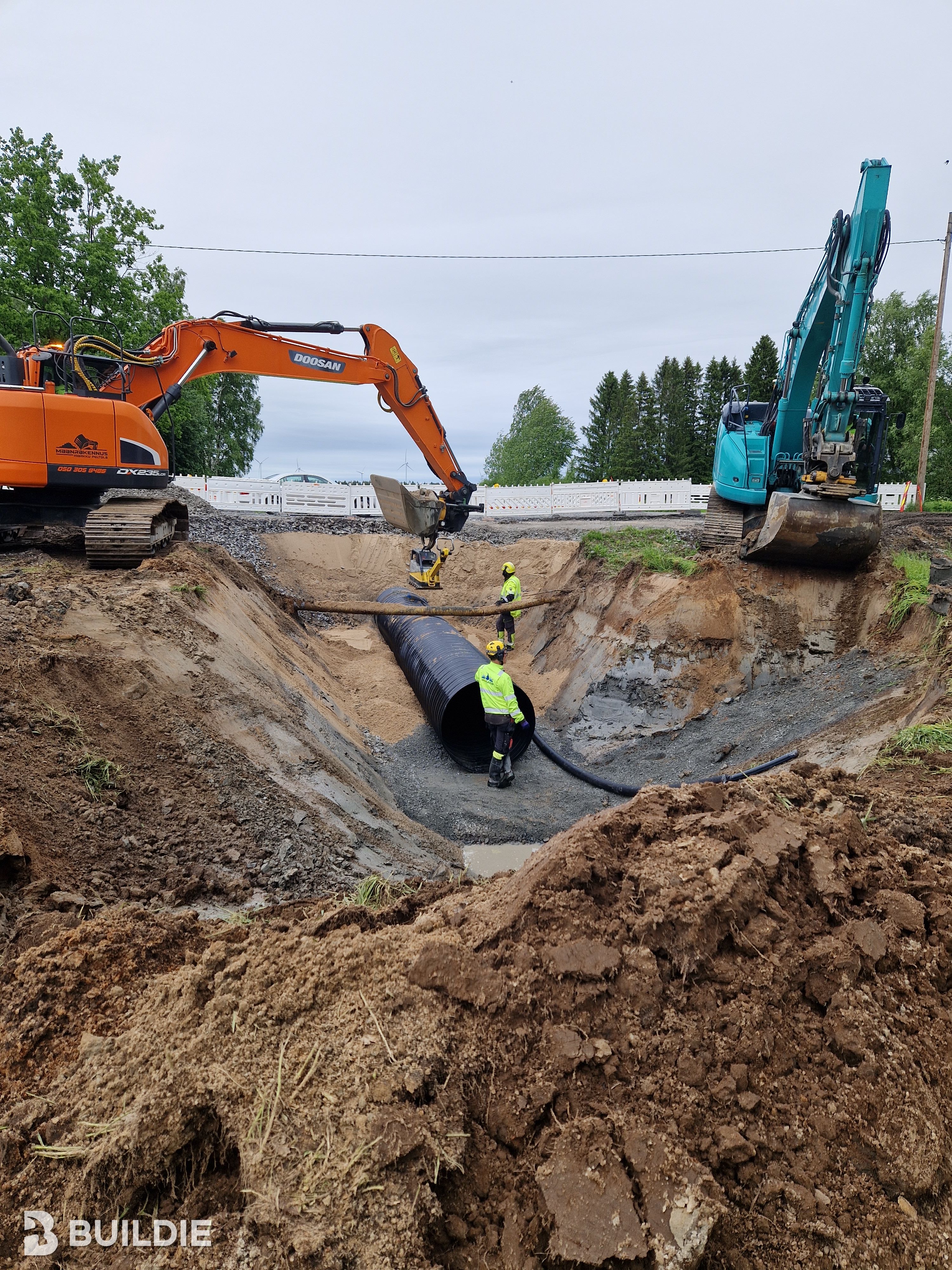 Kaksi kaivuria ja kaksi työmiestä viemärimonttua kaivamassa