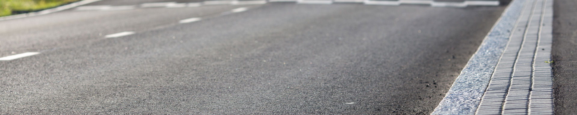 Asfalttitie ja reunakivetys.