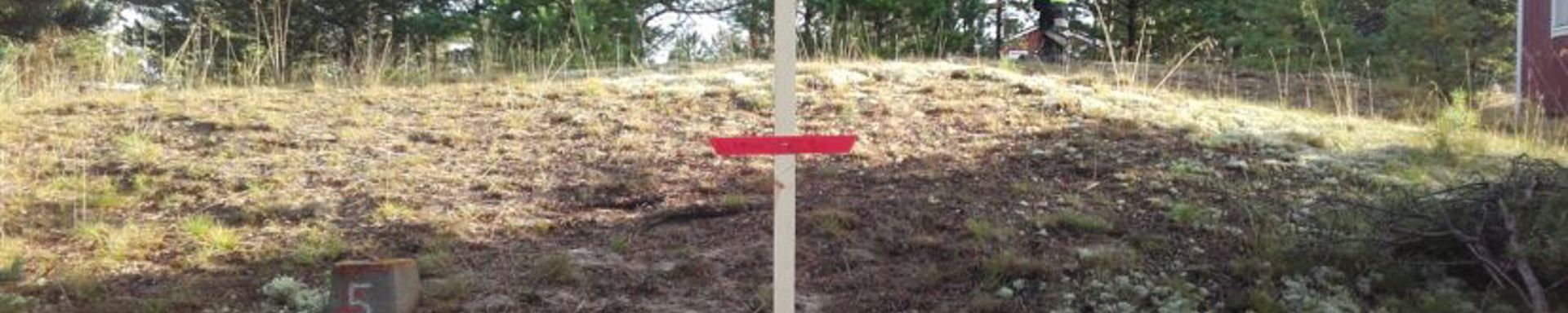 Merkki maastossa ja työmies taustalla.