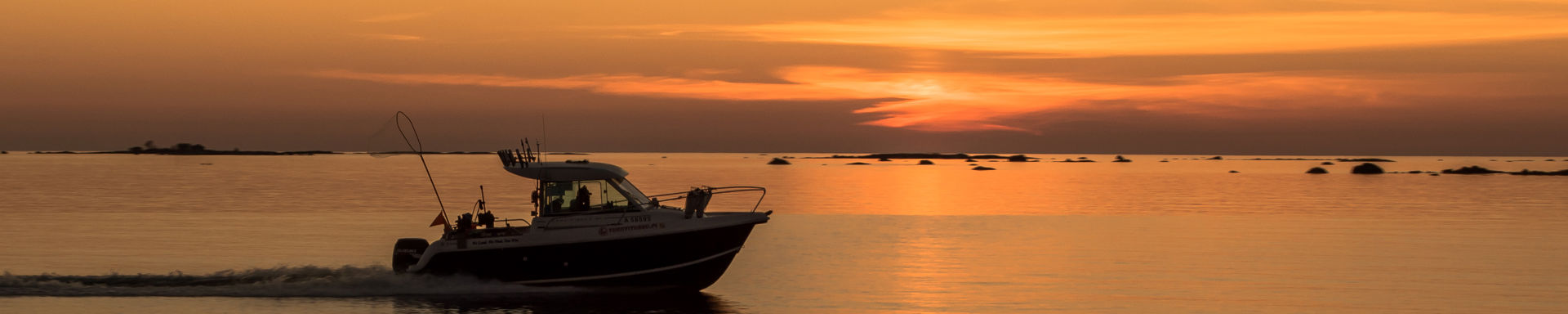 Auringonlaskun värjäämä oranssi merimaisema ja vene.