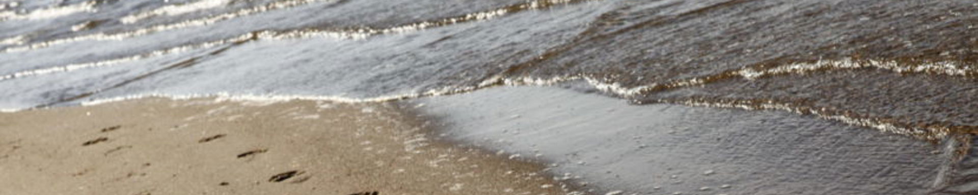 Jalanjäljet uimarannalla hiekassa.