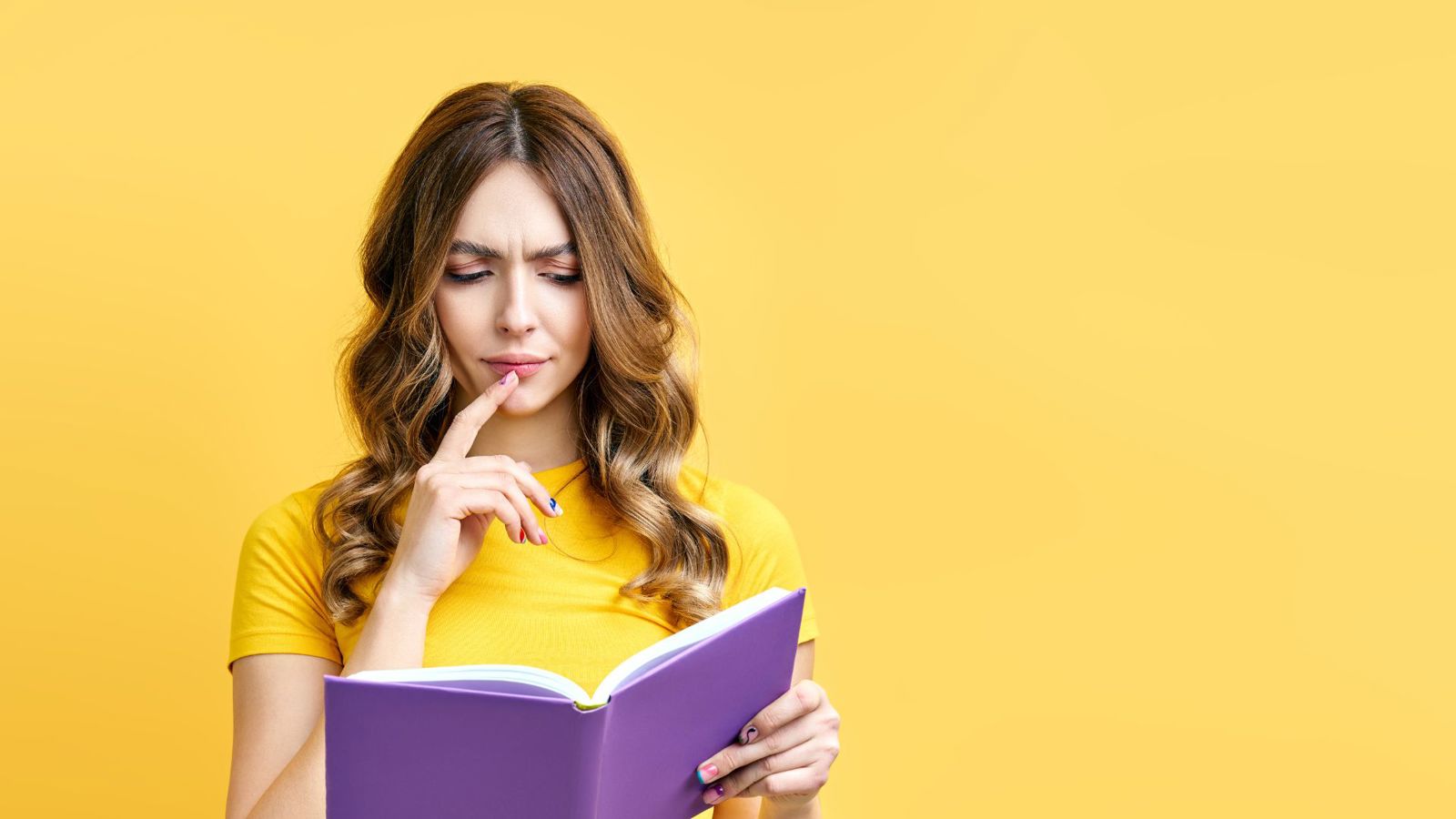 Nainen lukee opasta pohtiva ilme kasvoillaan.