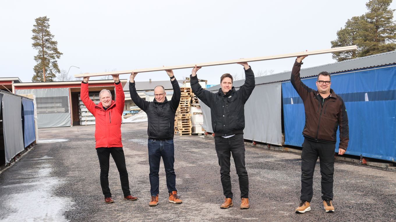 Neljä miestä kannattelee lankkua päidensä yläpuolella.