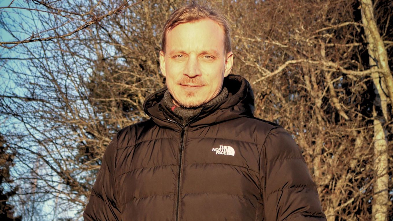 Mies seisoo puistossa auringonpaisteessa.