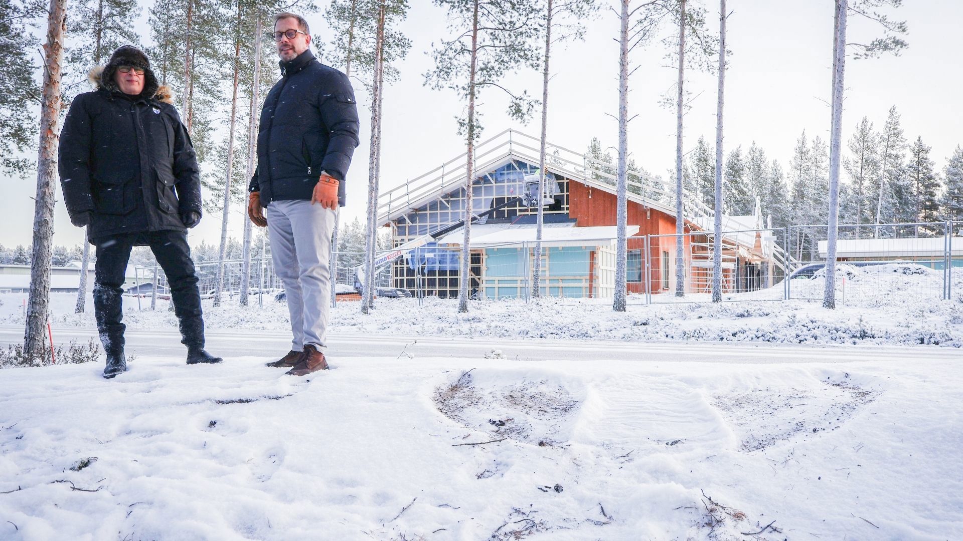 Jukka Puoskari ja Niko Rantanen seisovat lumisateessa, taustalla uusi päiväkoti.
