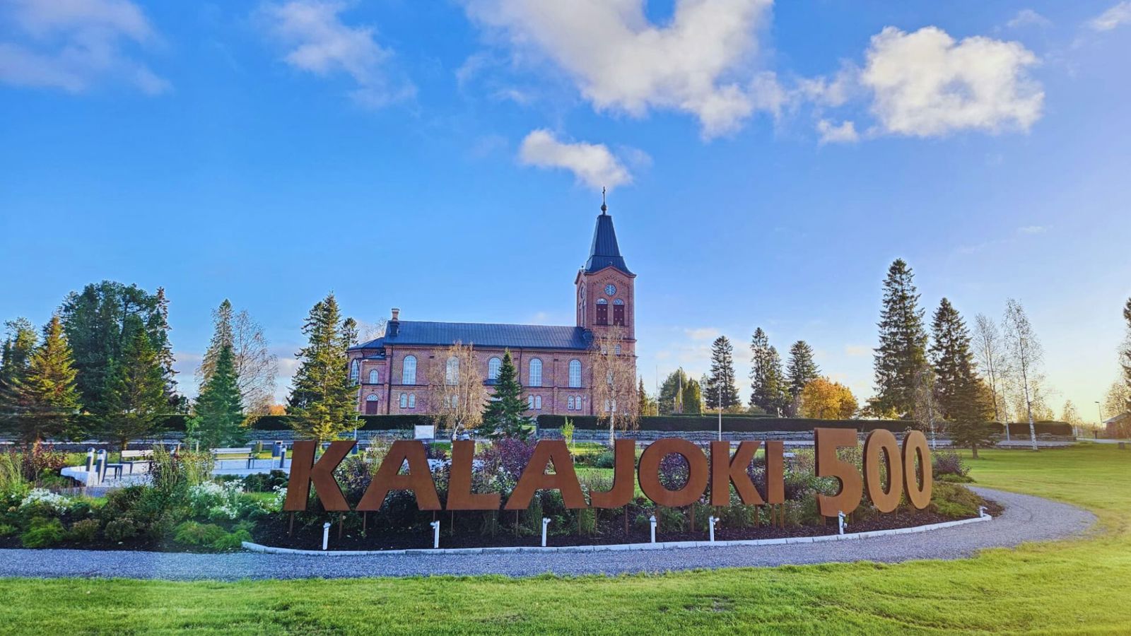 Kalajoen kirkko ja sen edessä oleva puisto syksyisessä asussaan.