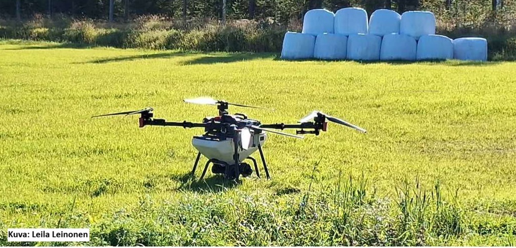 Kuvassa drone pellolla, taustalla heinäpaaleja, kuvaaja Leila Leinonen