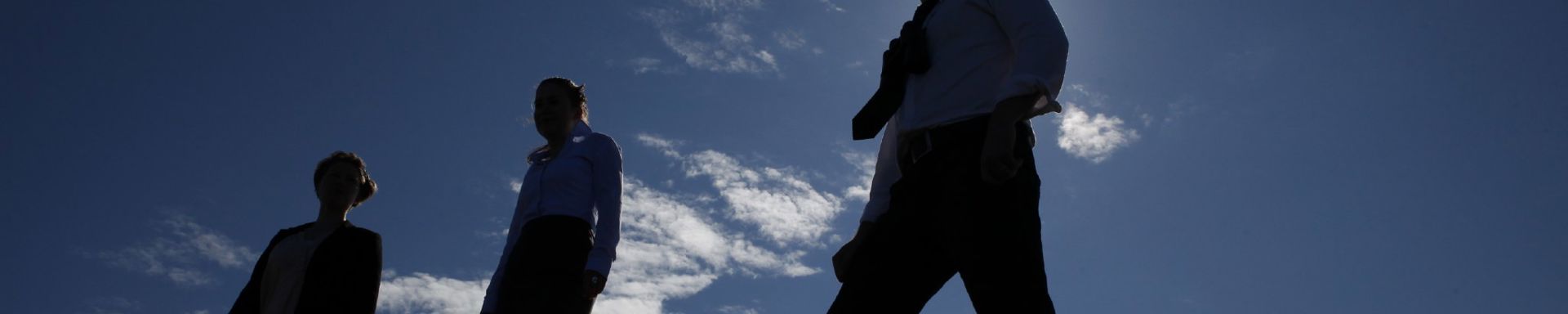 Kolme henkilöä auringonvalon pimentämänä.