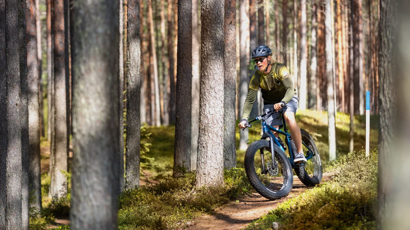 Mies pyöräilee metsässä syksyllä.