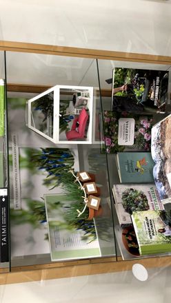 Vitriini, jossa on alahyllyillä puutarhakirjoja ja ylähyllyillä kevätaiheisia asetelmia.