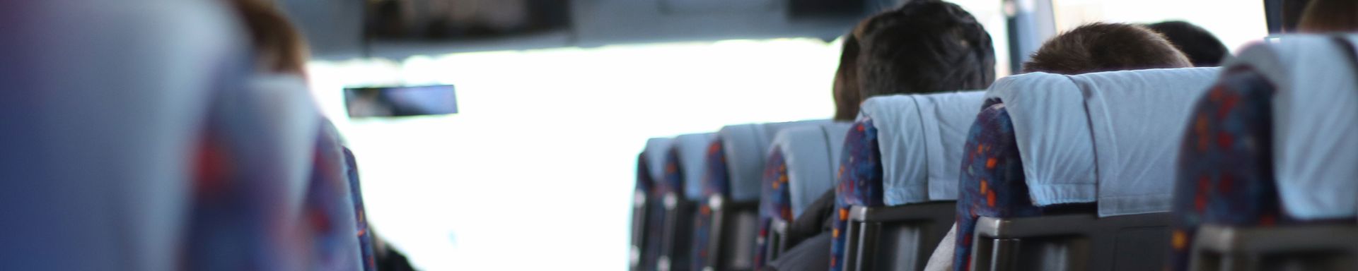 Linja-auton penkkejä ja matkustajia takaa kuvattuna.