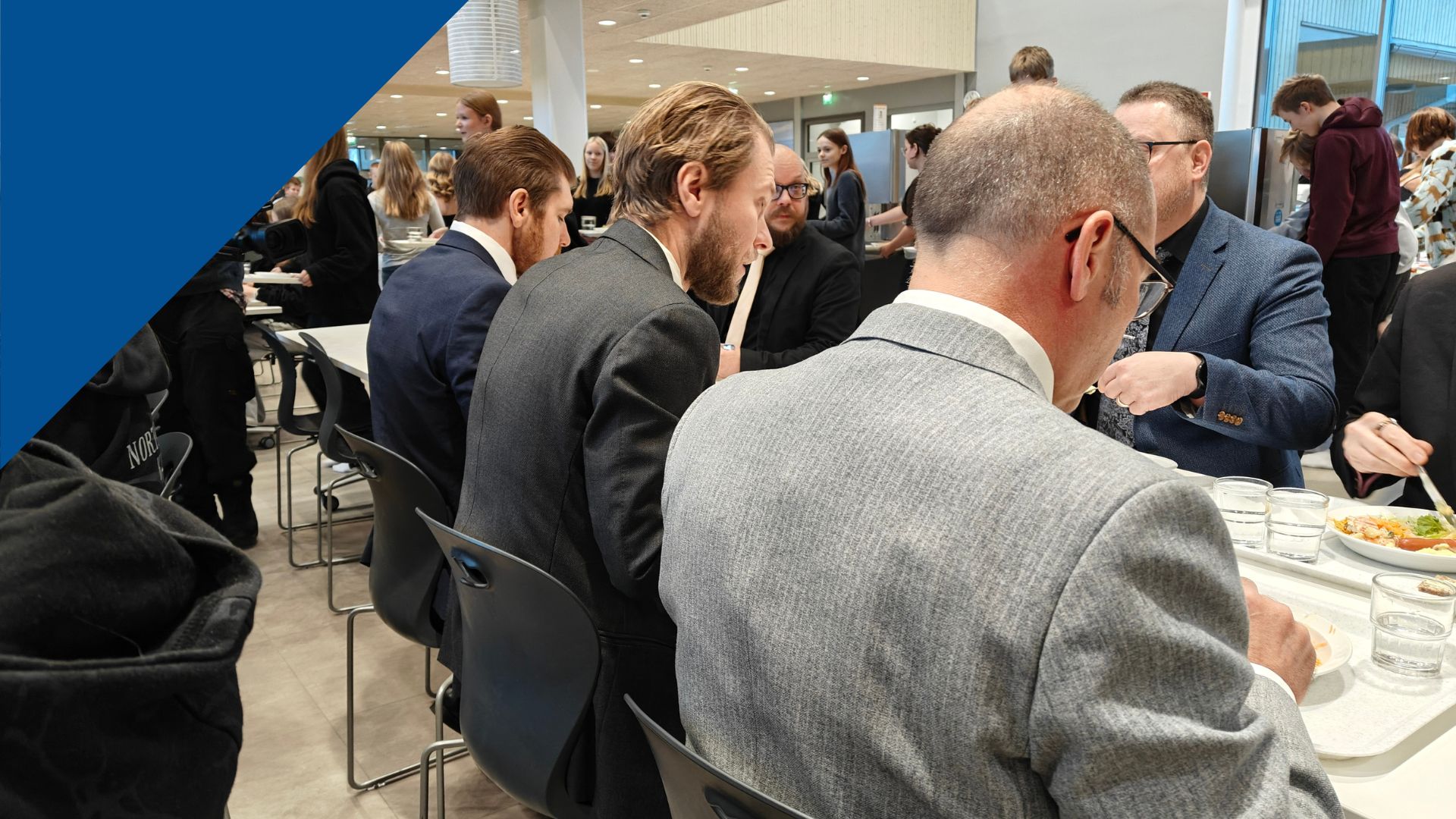 Koulun henkilökuntaa syömässä juhlapuvuissa