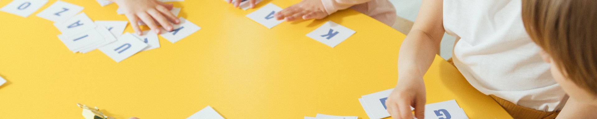 Lapsia pöydän äärellä pelaamassa kirjainpeliä.