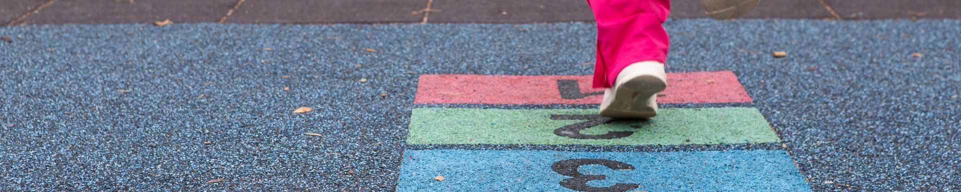 Lapsi hyppii maahan piirrettyä moniväristä ruutua.